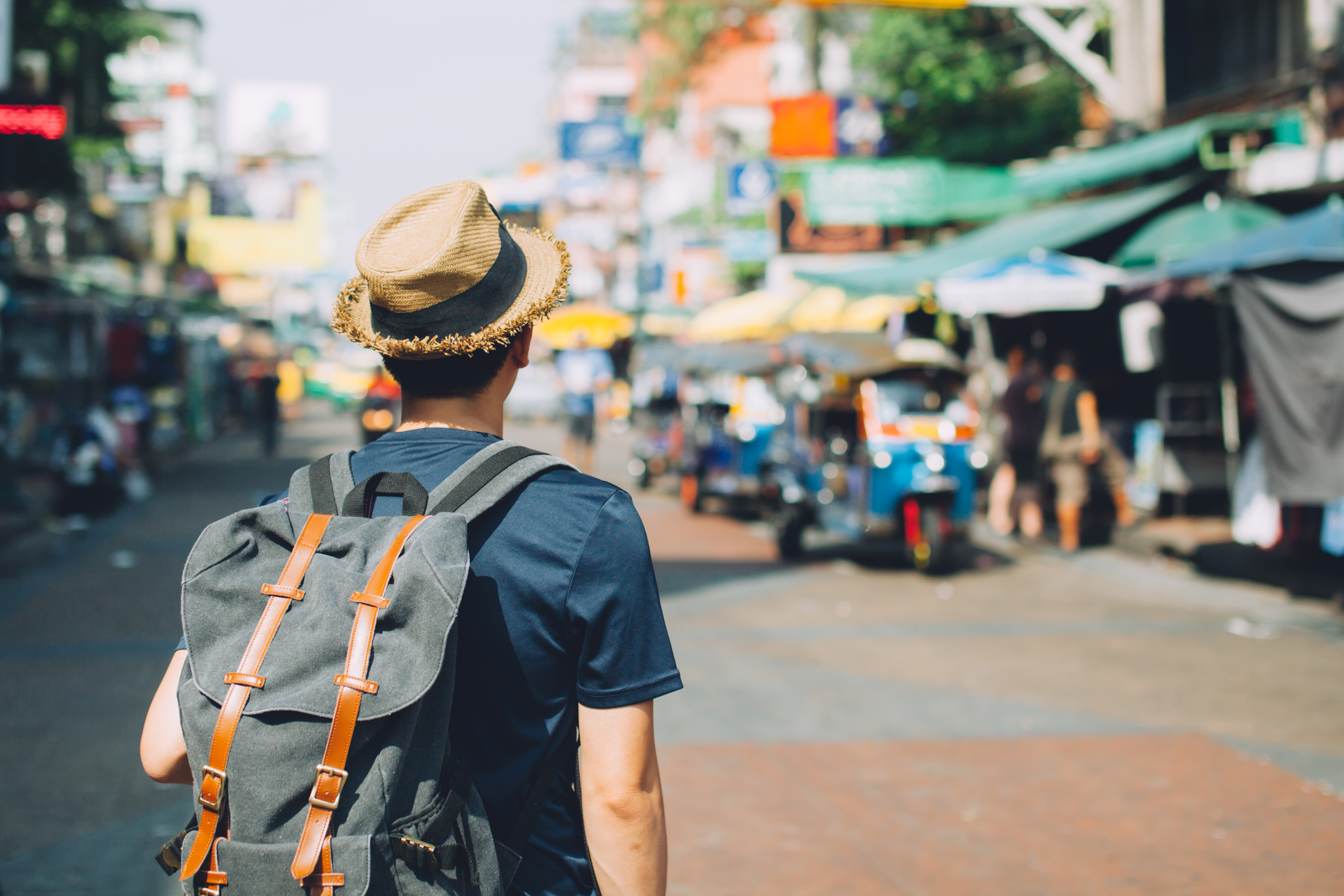 A man with a backpack walking through a busy street marketplace